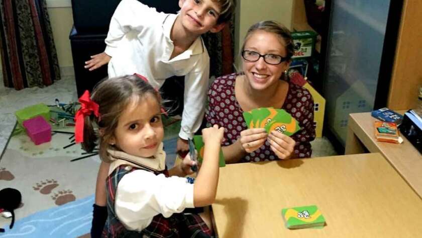 Language Assistant playing cards with her host siblings