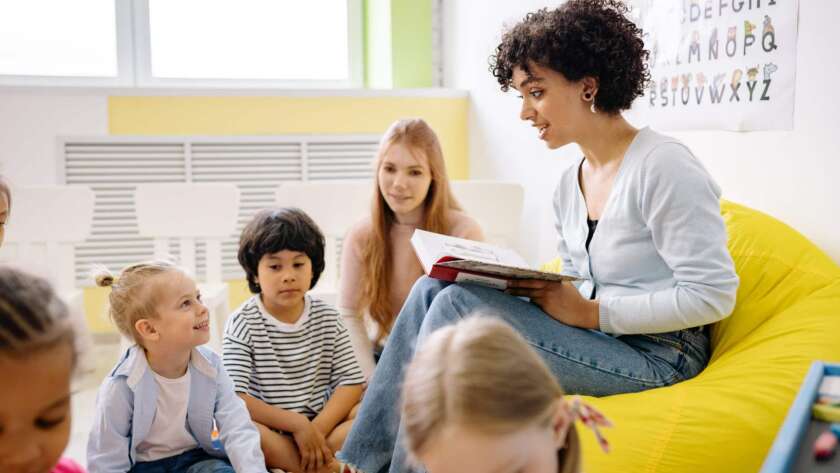 Early Childhood Educator reading a book to a group of toddlers